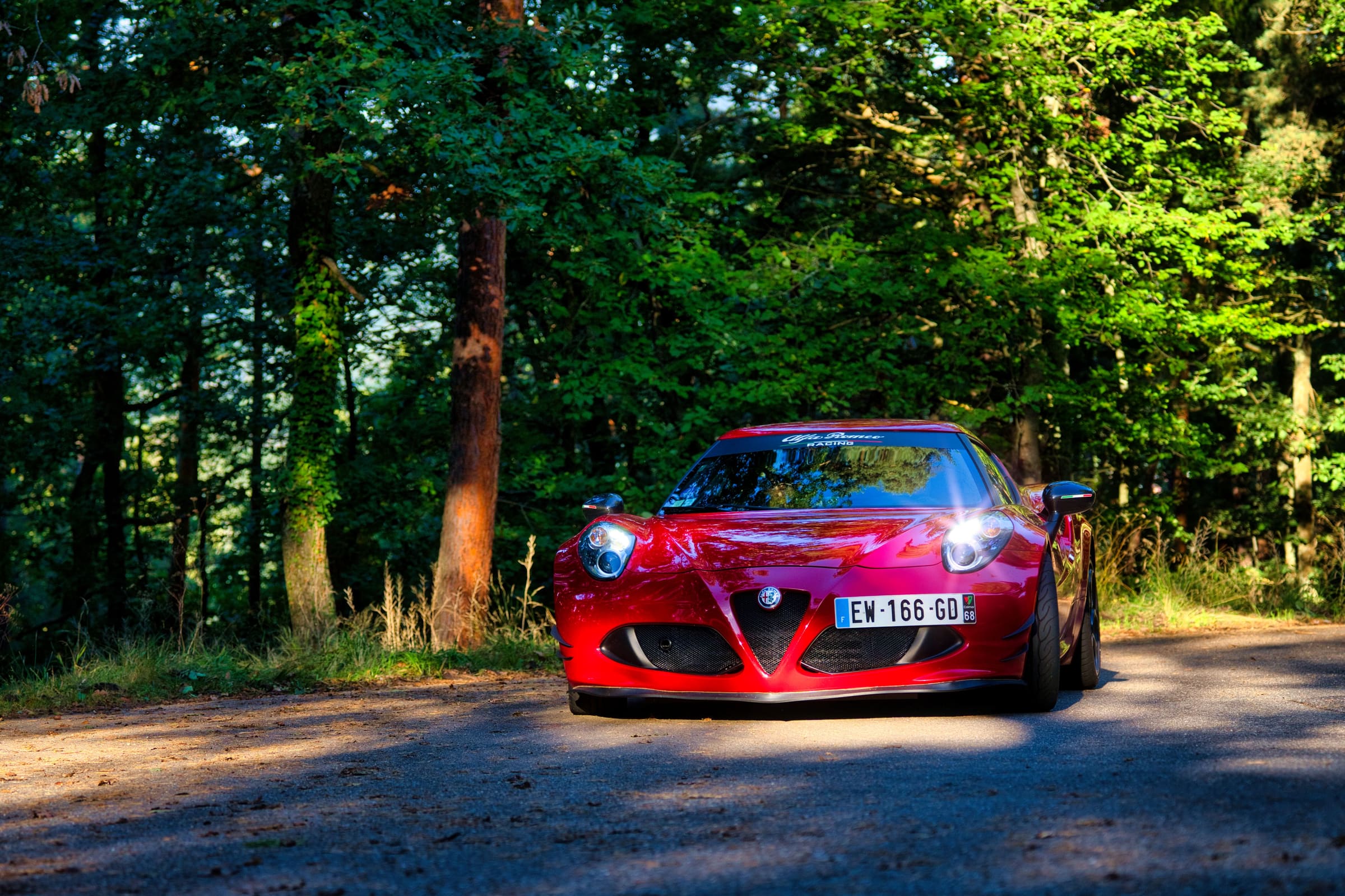 Alfa Romeo 4C rouge à l'arrêt sur une route forestière